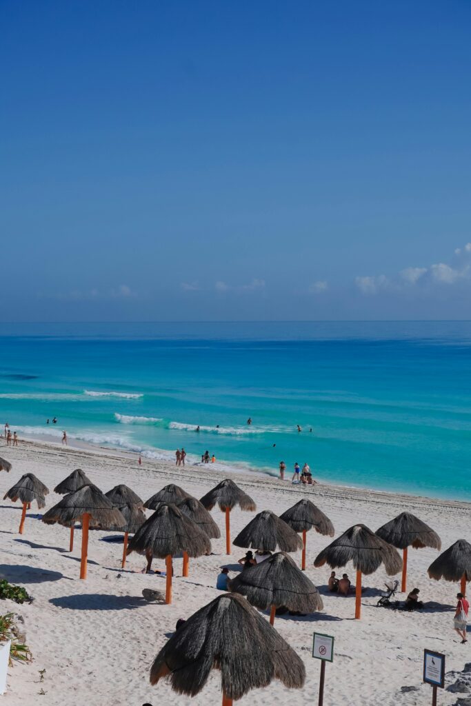 Beautiful Cancun beachscape with turquoise waters and thatched umbrellas.